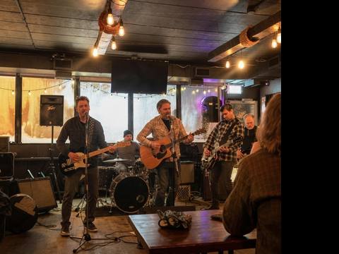 The Threads playing at a warm bar with Edison bulbs and audience at tables